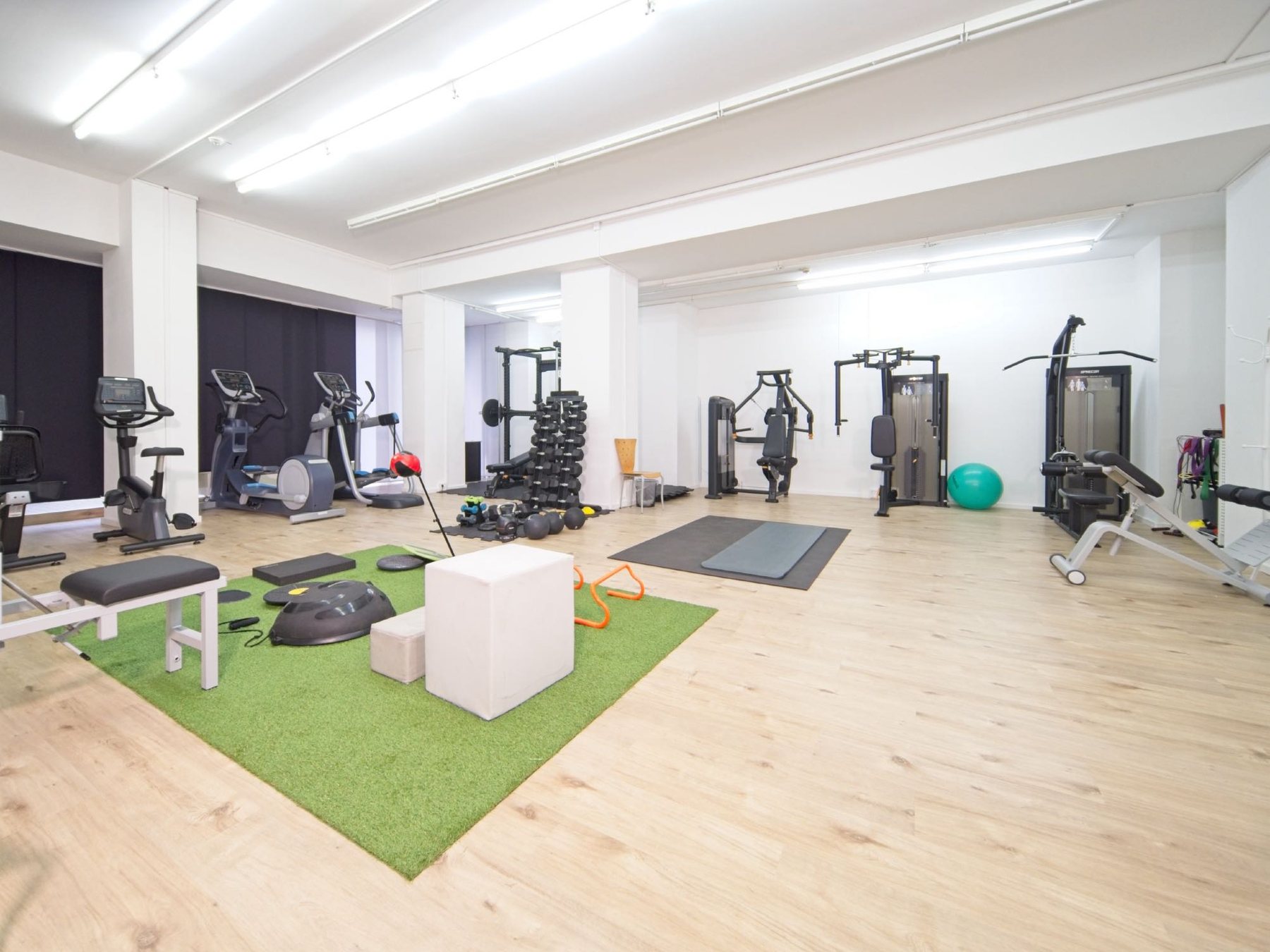 Der Trainingsraum der Praxis mit Kraftgeräten, Cardiogeräten, Hantelbereich und Funktionsfläche